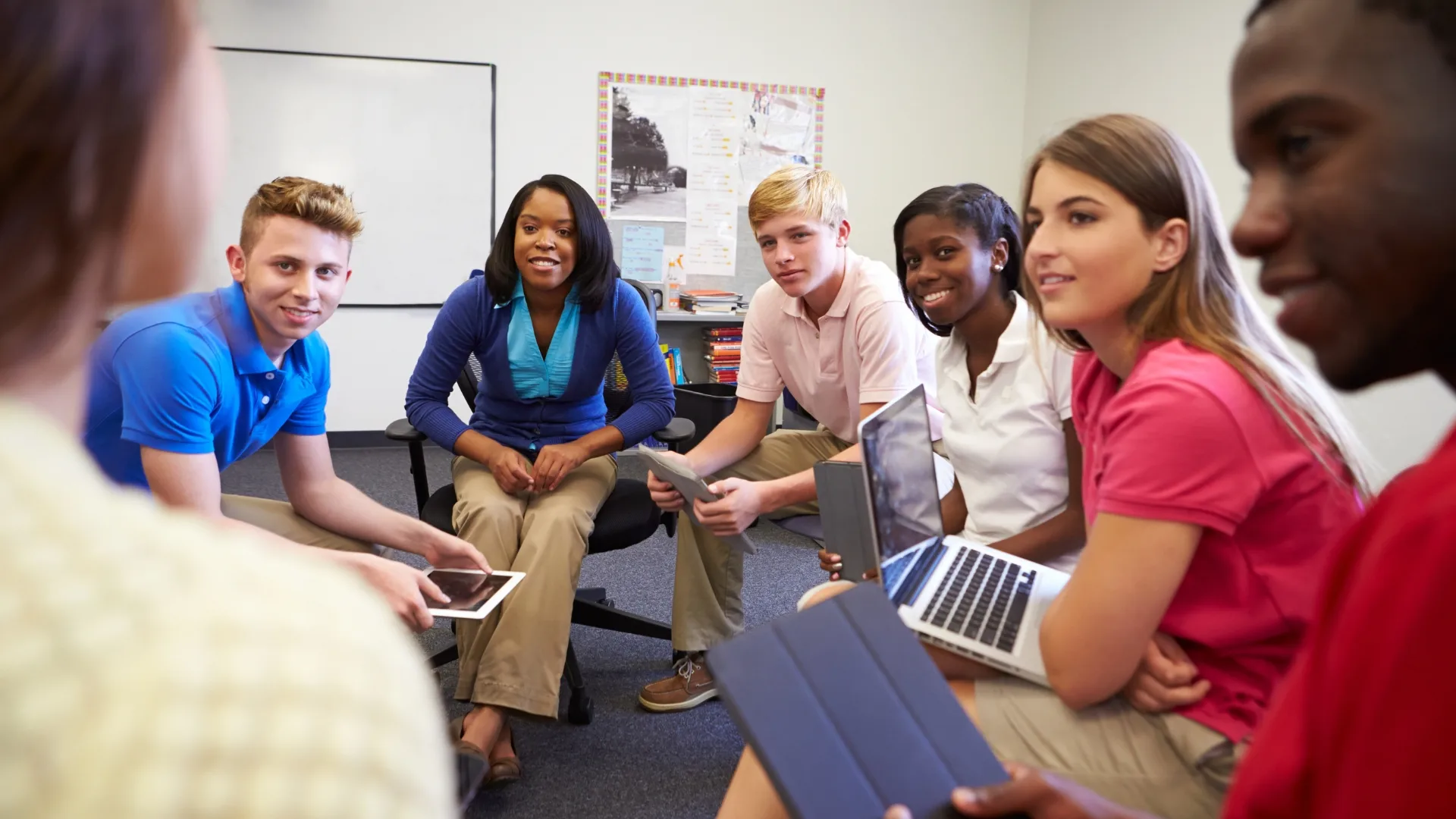 Middle school students discussing their work with laptops